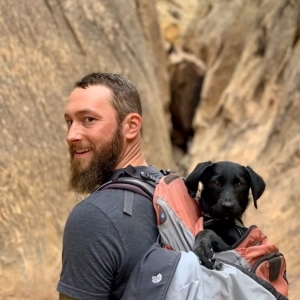 Joel hiking with his puppy Rio in his backpack