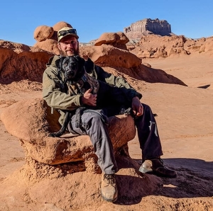 Joel sitting in Goblin Valley with his dog Rio